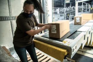 UPS worker unloads boxes from semi trailer truck onto conveyor belt